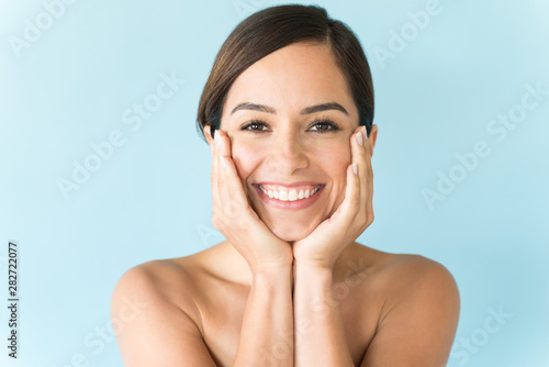 Female With Hands On Face Against Plain Background