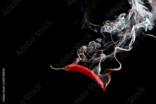 Red chili with smoke on a black background, the concept of spicy