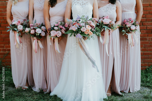 bride and bridesmaids holding wedding bouquets, pink bridesmaids dresses, detail shot, copy space