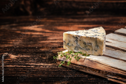 Blue cheese close up on an old wooden table. horizontal macro. mold. free space for text