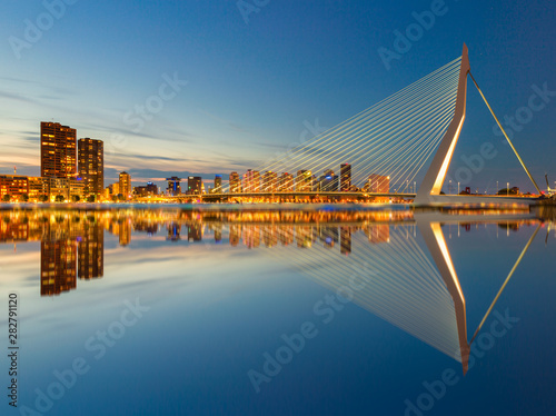 The Erasmusbrug and the Rotterdam skyline by night with a reflection in the water, a famous landmark in the Netherlands and travel destination