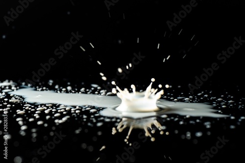 Milk spilled on black surface, closed up, selective focus