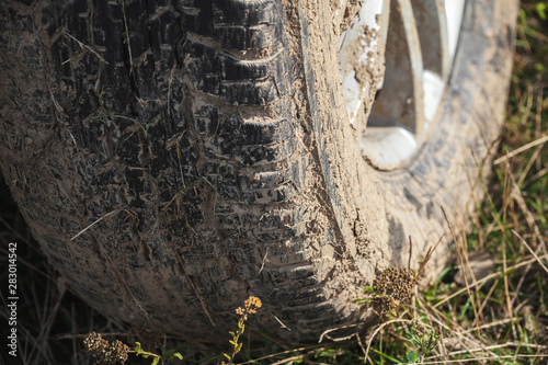 Muddy car wheel is on the grass, close up