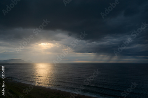 dark seascape with stormy clouds and rain at sunset