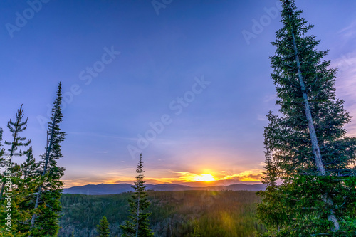 Sunrise above forest and mountains