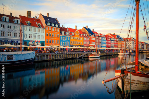 Nyhavn Harbour at sunset in Copenhagen Denmark with colorful houses reflection and a boat