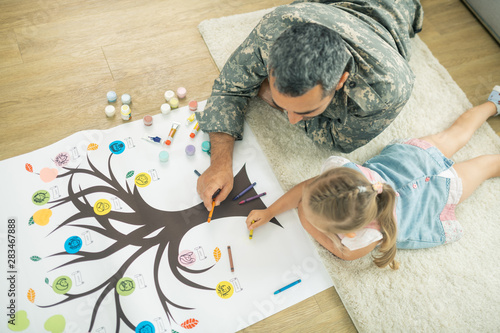 Father and daughter lying on the floor and painting family tree