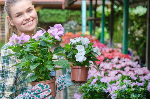 Young adult woman gardening in a greenhouse, planting some flowers