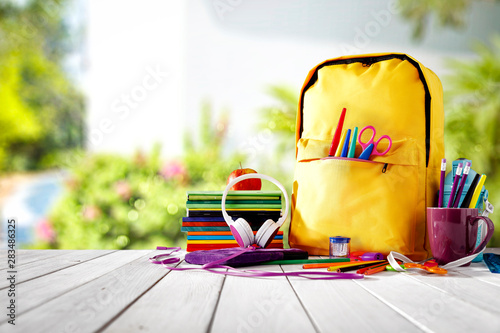 Table background and a schoolbag with some colorful school supplies. Empty space for advertising products and decoration.