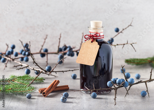Homemade sloe liquor in a glass bottle with greeting card as small present for Christmas. Selective focus. Copy space.