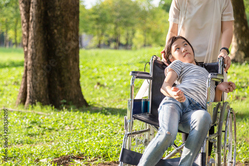 Sick child girl with cerebral palsy in wheelchair outdoor park or daughter suffering from seizures,illness with epilepsy,asian mother or caregiver care of girl patient,brain,mental retardation concept