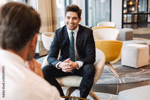 Happy businessmen colleagues indoors in business center office talking with each other.