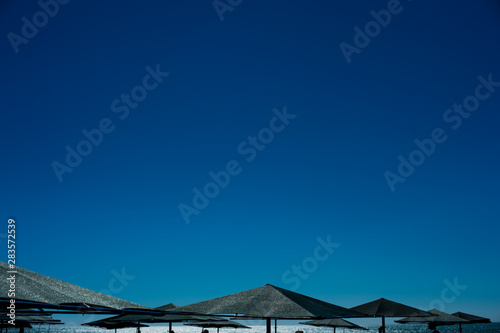 Relaxing beach background with umbrellas, sea and blue clear sky