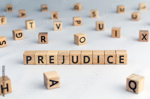 prejudice - word from wooden blocks with letters, personal opinions prejudice bias concept, random letters around, white background