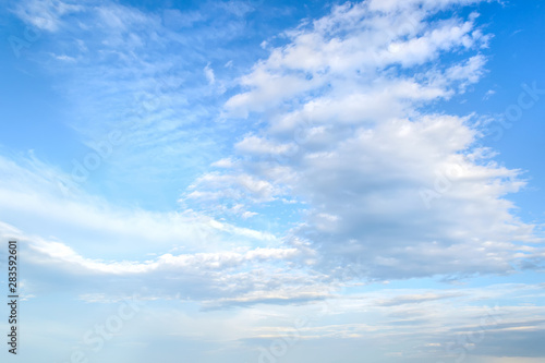 White light fluffy stratus and cirrus clouds high in the blue summer sky. Different cloud types and atmospheric phenomena.