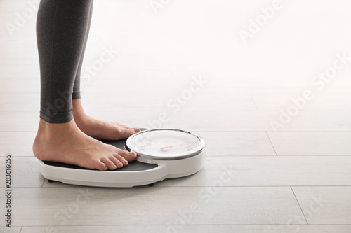 Woman standing on scales indoors, space for text. Overweight problem