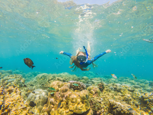 Happy woman in snorkeling mask dive underwater with tropical fishes in coral reef sea pool. Travel lifestyle, water sport outdoor adventure, swimming lessons on summer beach holiday