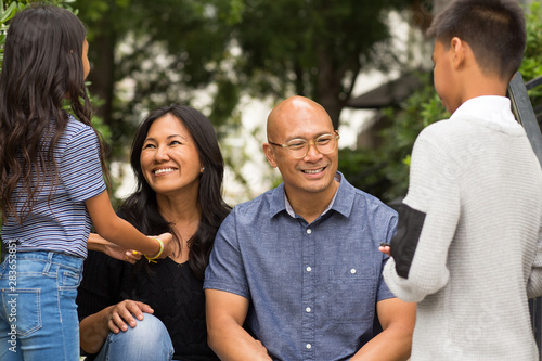 Portrait of an Asian family laughing and talking outside.
