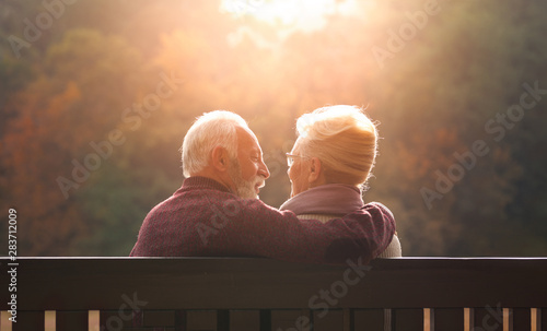 Senior couple sitting on bench in autumn park