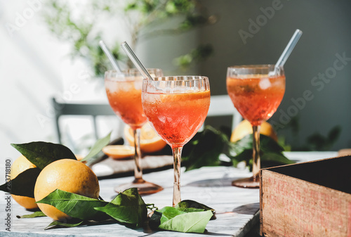 Aperol Spritz aperitif alcohol cocktail in glasses with fresh oranges and ice on grey marble board, selective focus, close-up. Summer refreshing drink concept