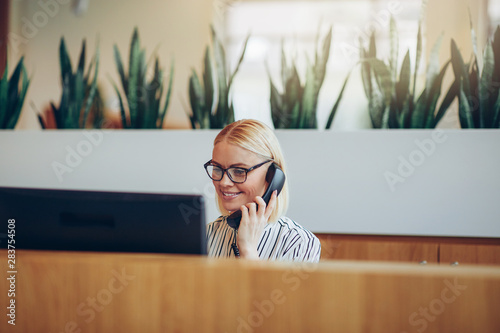 Smiling businesswoman talking on the telephone at a reception de