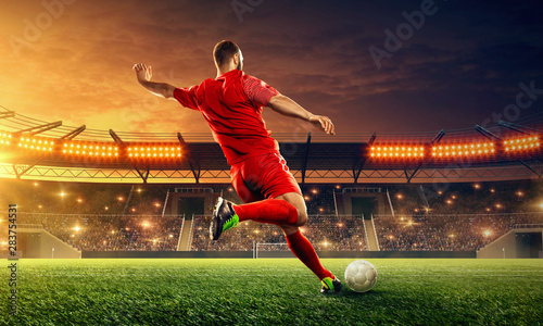 Soccer player kicks a ball. Night illuminated soccer stadium with dramatic sky