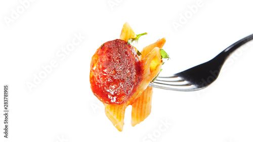 Italian Pasta with Salami, Cold Smoked Tomatoes, Onion, Garlic, Fresh Basil, Parsley, Sweet Chili Sauce, Bulgarian Pepper Close Up. Macro Photo of Yummy Penne with Greens on Fork, Selective Focus