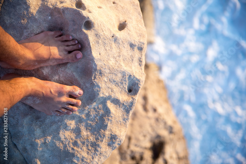 man's feet standing on a cliff in-front of the sea 