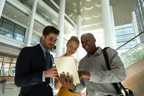 Diverse young business people with tablet talking in a modern atrium