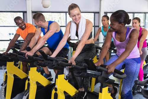 Fit people exercising on exercise bike in fitness center