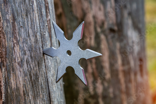 Shuriken (throwing star), traditional japanese ninja cold weapon stuck in wooden background