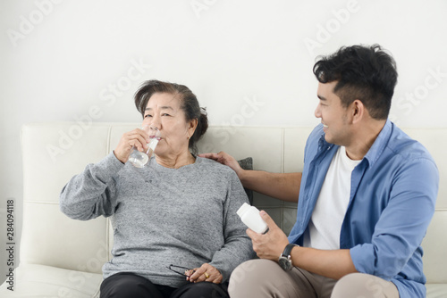 Asian man giving medicine to his mother, lifestyle concept.