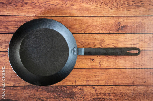 Isolate carbon steel skillet pan on a wooden background - overhead top view
