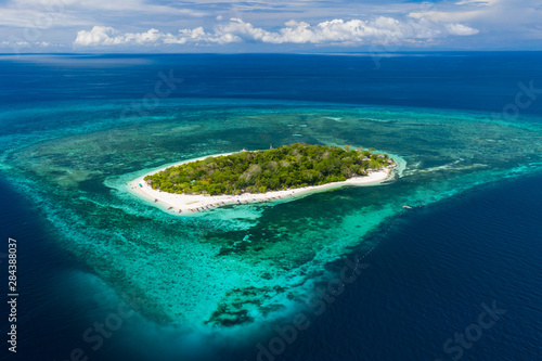 Aerial drone view of a beautiful tropical island surrounded by coral reef (Mantigue Island, Camiguin, Philippines)