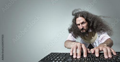 Funny portrait of a skinny nerd working with a computer