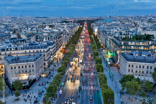 View from top of Arc de Triomphe in evening light with city lights and streets below, Paris, France.