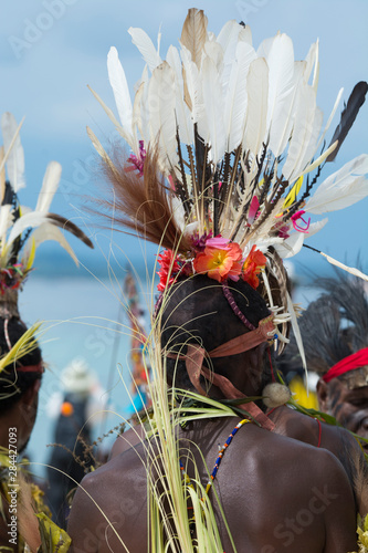 Melanesia. Small island of Ali off the coast of mainland Papua New Guinea. Local villagers in traditional feather headdresses performing welcome dance and sing-sing with ocean in the distance.