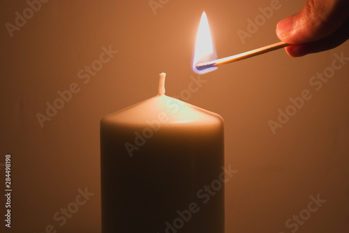 Lighting a candle with a burning match