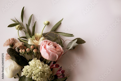 Horizontal image of fresh cut, pastel flowers and greenery on a white background with copy space