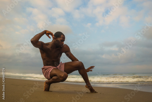 contemporary dance choreographer and dancer doing ballet beach workout . a young attractive and athletic black African American man dancing in dramatic performance