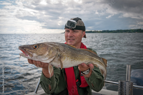 Happy angler with cod fishing trophy
