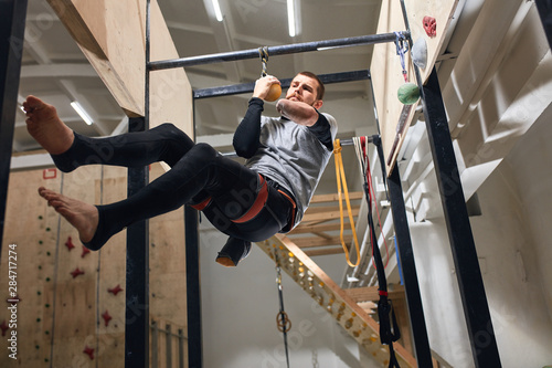 Low angle view of physically challenged rock-climber preparing to the international bouldering competition, doing dynamic and intentinsive trainings, powerful and strong willed person.