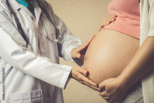 Happy pregnant woman visit gynecologist doctor at hospital or medical clinic for pregnancy consultant. Doctor examine pregnant belly for baby and mother healthcare check up. Gynecology concept.