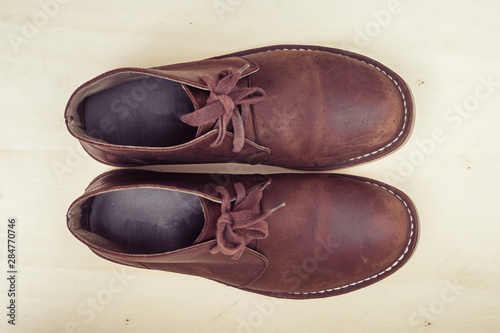 Brown stylish boots on wood background, retro color