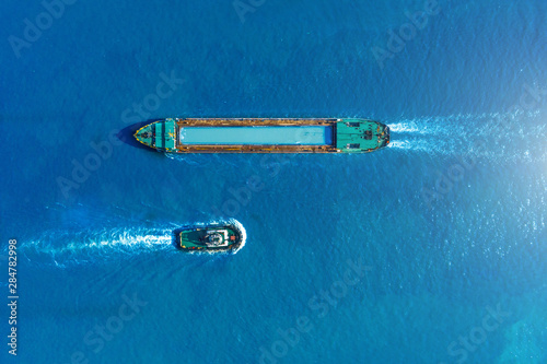 Cargo ship barge and tugboat sail to meet each other in the seaport of the port, aerial view.
