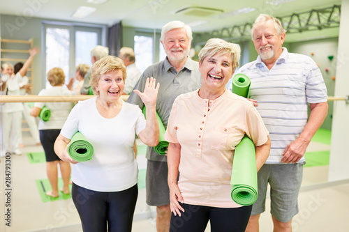 Glückliche Senioren mit Yogamatten im Sportstudio