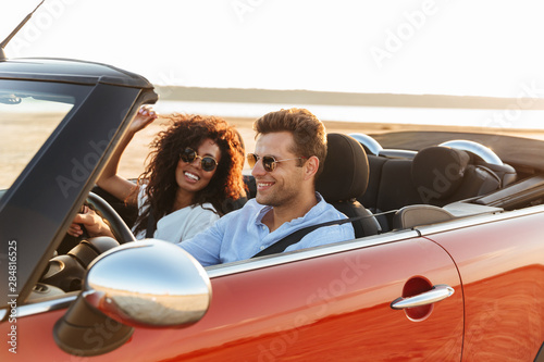 Beautiful young multiethnic couple riding in a convertible