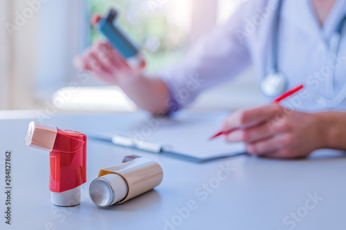 Doctor writes medical prescription for asthma inhaler to asthmatic patient during medical consultation and examination in hospital. Healthcare