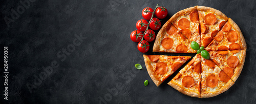 Tasty pepperoni pizza on black concrete background. Top view of hot pepperoni pizza. With copy space for text. Flat lay. Banner