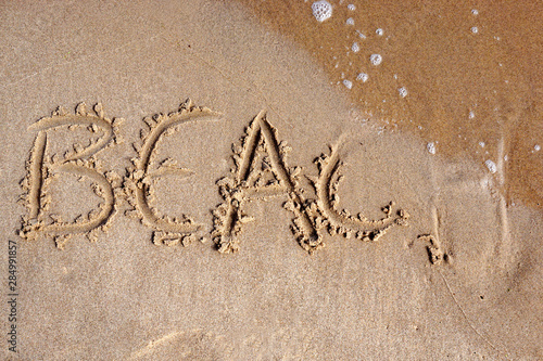 The word beach written in the sand on a beach